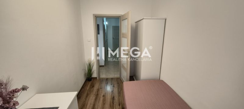 A bright room in a 3-room apartment with a bed, wardrobe, and wooden decor flooring.