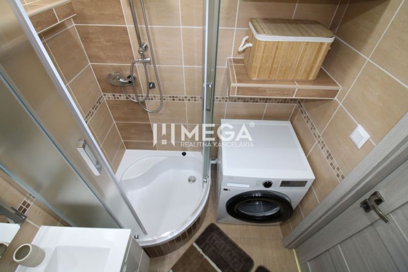 A bathroom with a shower and a washing machine in a 3-room apartment, with brown tiles.