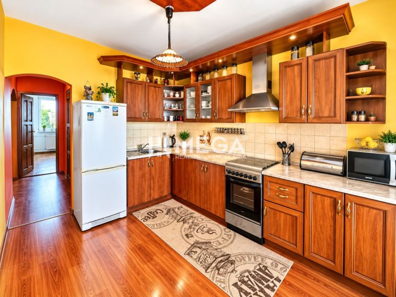 A kitchen with yellow walls, a wooden decor floor in a 4-room apartment.