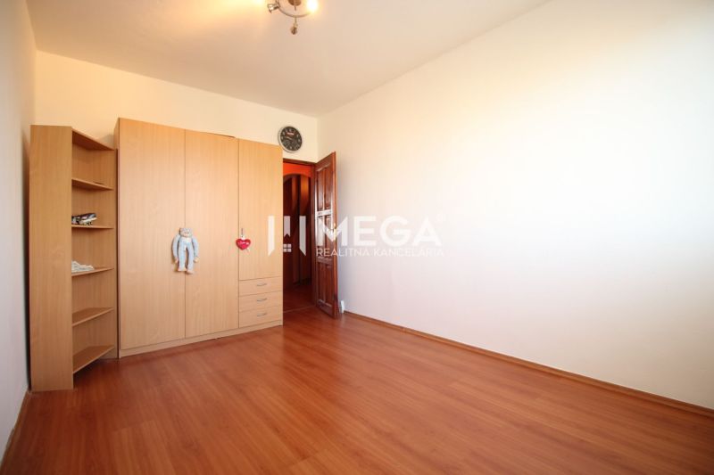 A room in a 4-room apartment with a wooden decor floor and a wardrobe.