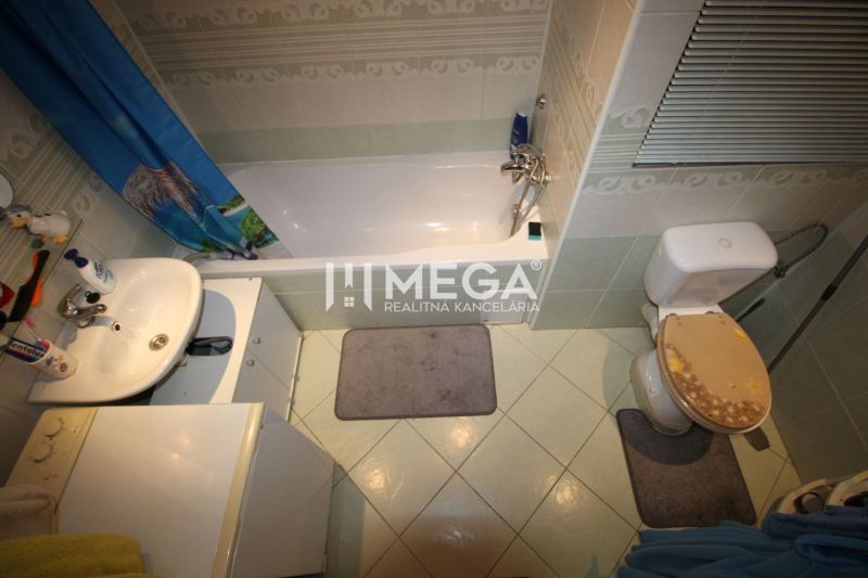A bathroom in a 4-room apartment with a bathtub, sink, and toilet with rugs.