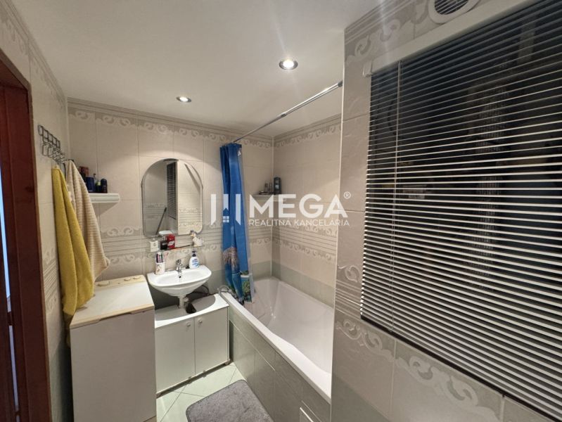 Bathroom in a 4-room apartment with a bathtub, sink, mirror, and window with a blind.