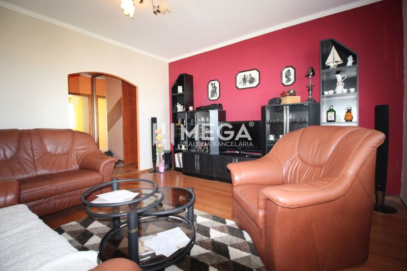 A living room with brown furniture, a red wall, and a floor with a wood pattern in a 4-room apartment.