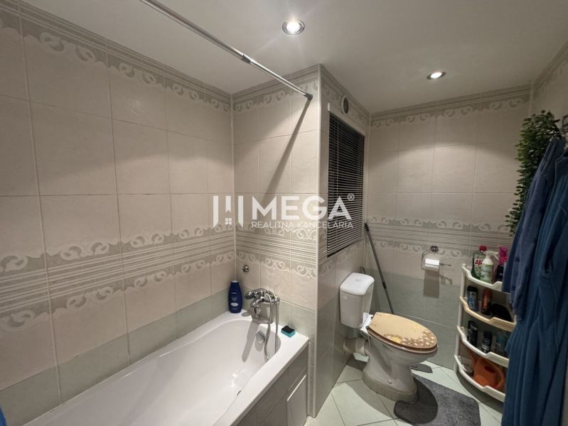 Bathroom with a shower bathtub and toilet in a 4-room apartment, tiles with ornaments.