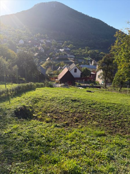 A residential plot in Košecké Podhradie surrounded by nature and houses, beneath mountain peaks.