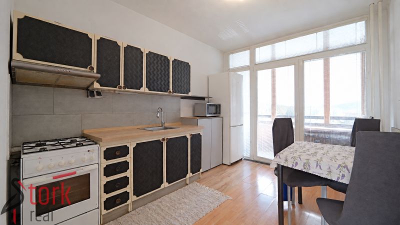 A kitchen in a 3-room apartment with a wooden decor floor and a dining area.