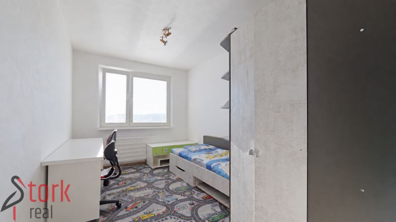 Children's room in a 3-room apartment with a bed and a desk on a colorful carpet.