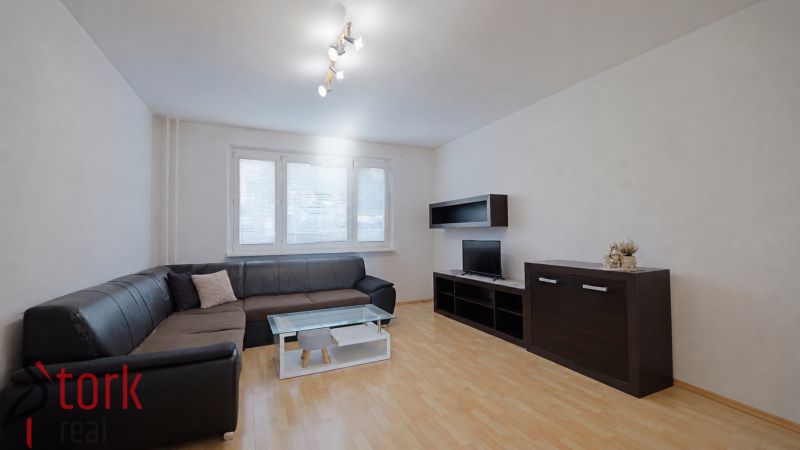 Living room with a black sofa set, cabinets, and a floor with a wood decor, 3-room apartment.