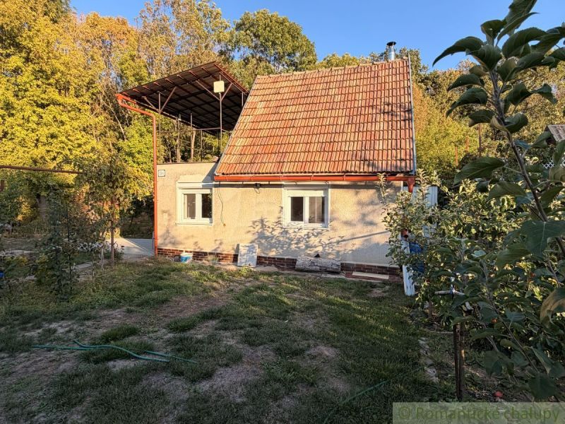 A cottage in Nové Zámky, surrounded by greenery, with a red roof in a natural setting.