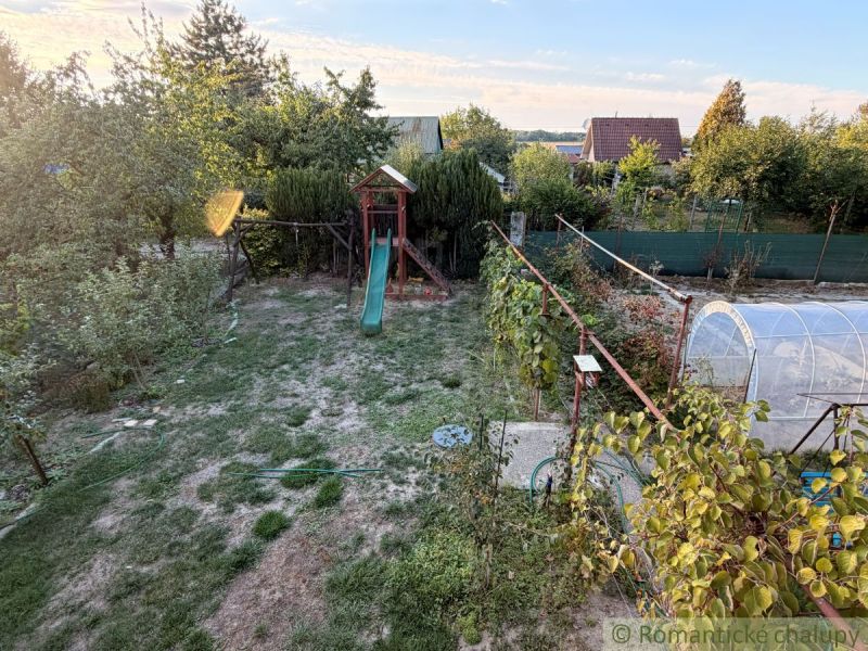 A garden with a lawn and a slide near the cottage in Nové Zámky.