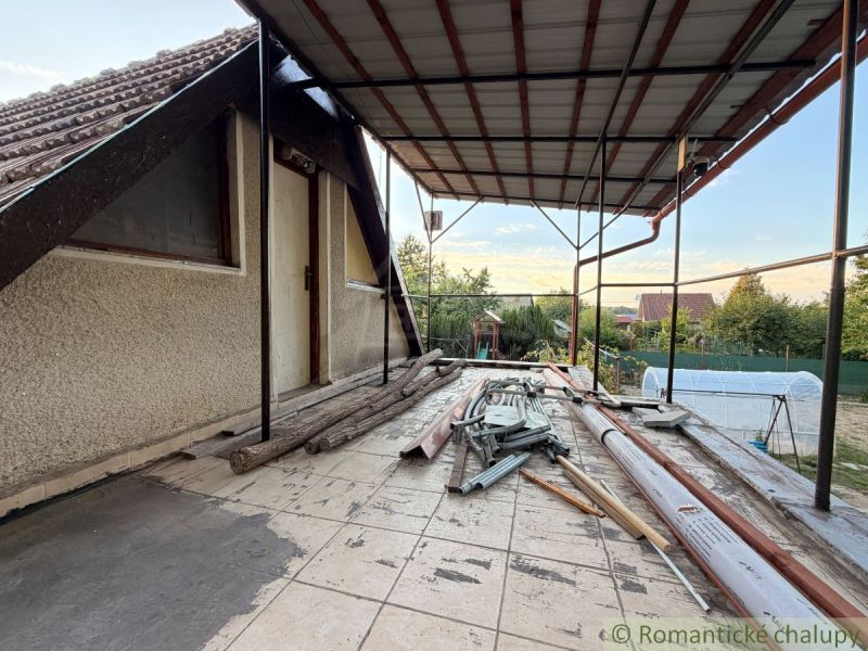 The terrace of the cottage in Nové Zámky with clutter and building materials, a peaceful garden in the background.