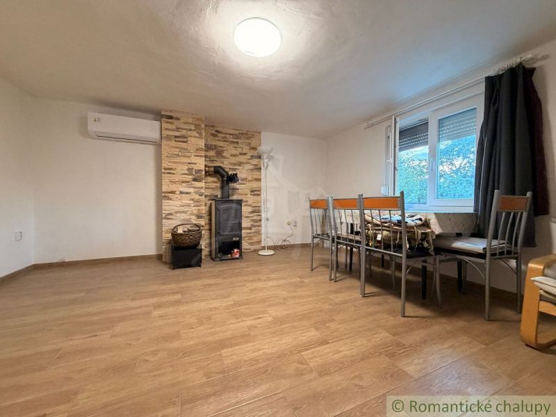 The interior of a cabin with a wood-patterned floor, a fireplace, and a dining area.