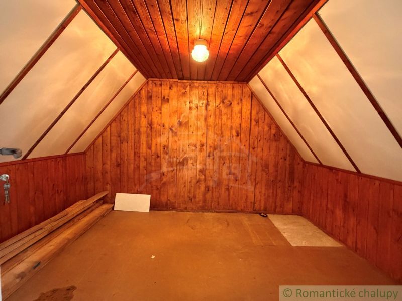 Attic room in a cabin with wooden paneling and flooring.