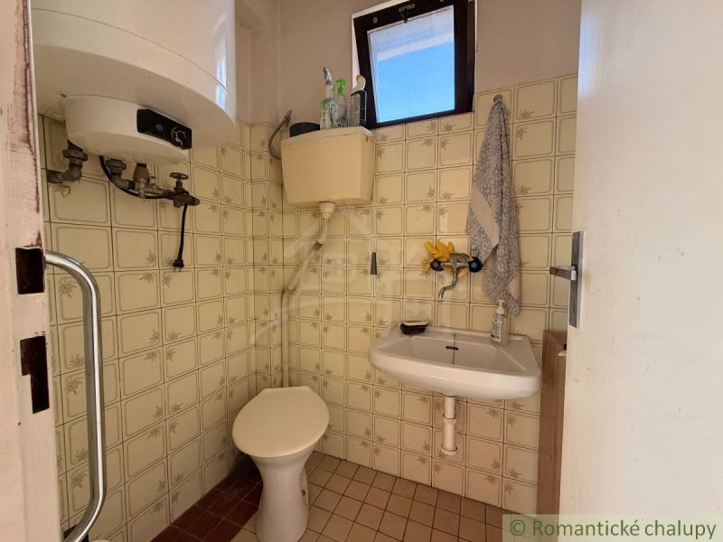 A bathroom in a family house with a toilet, tiles, and retro-style tiling.