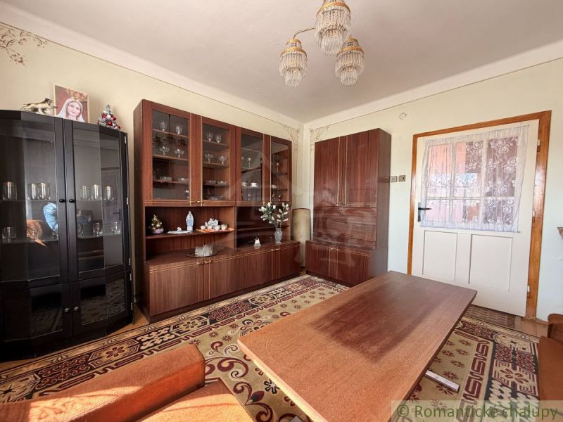 Living room in a family house with cabinets, a table, and a patterned carpet.