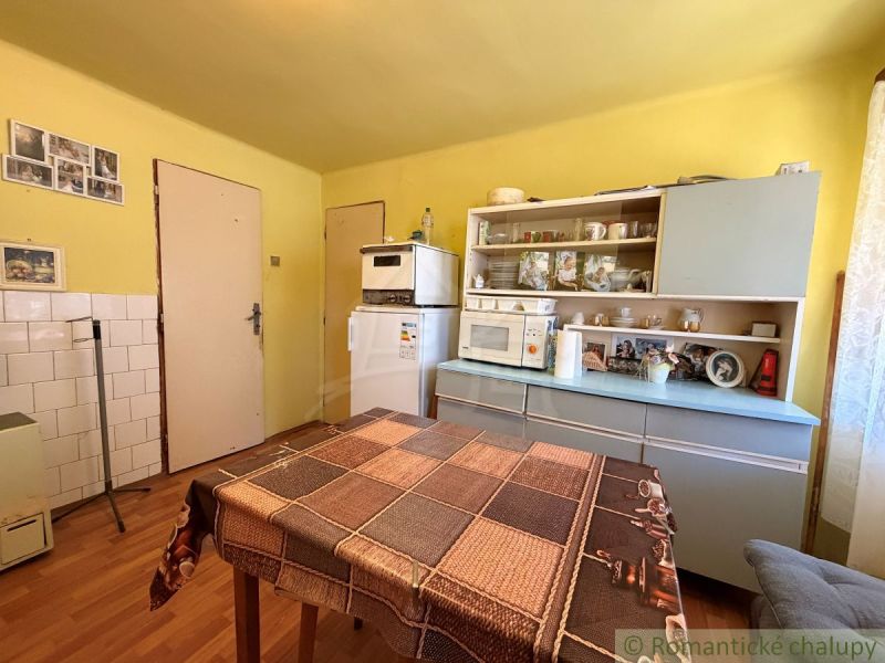 A kitchen in a family house with a wooden decor floor and older furniture.