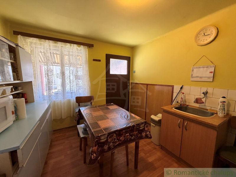 A kitchen in a family house with a wood-patterned floor and yellow walls.