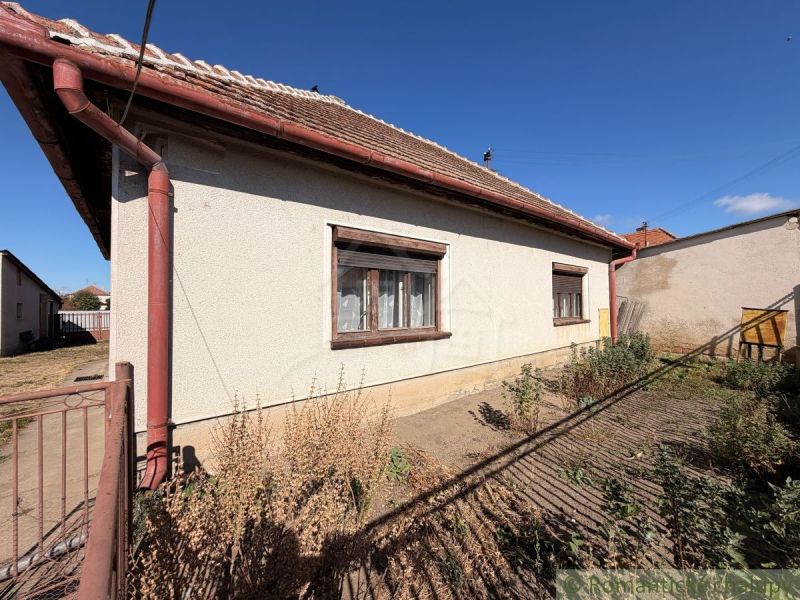 A family house in Hurbanovo with a white facade, brown shutters, and a garden behind the house.