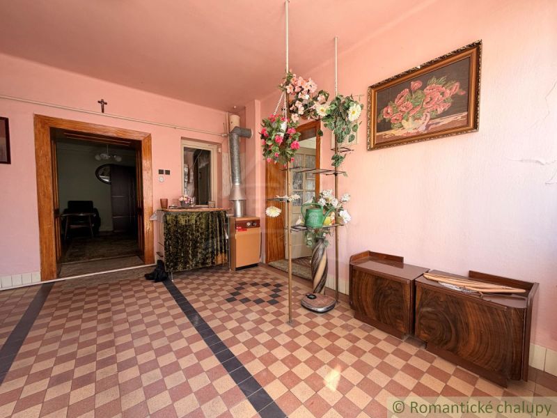 The interior of a family house with pink walls, floral decorations, and a checkered floor.