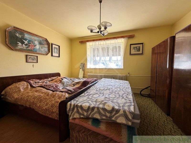 A bedroom in a family house with a bed and a furniture wall, with paintings on the wall.