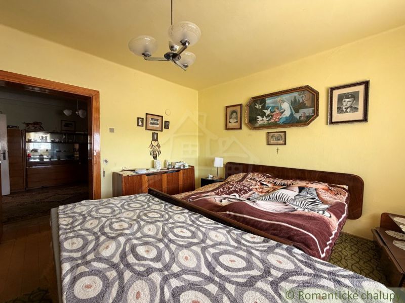Bedroom in a family house with decorative blankets and wall paintings.