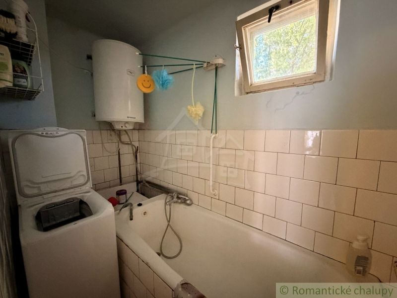 Bathroom in a family house with a bathtub, boiler, and washing machine.