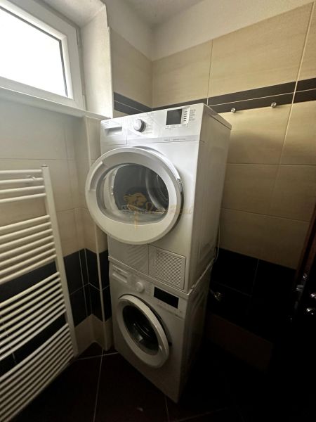 Bathroom in a 2-room apartment with a washing machine and dryer stacked on top of each other.