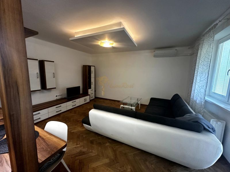 Living room with a sofa, TV, cabinets, and a wooden decor floor in a 2-room apartment.