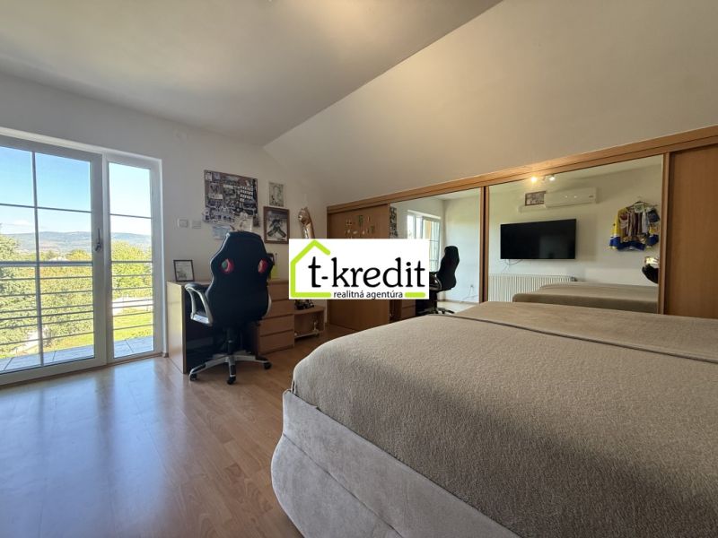 A bedroom in a family house with a wooden decor floor, a mirrored wardrobe, and balcony doors.
