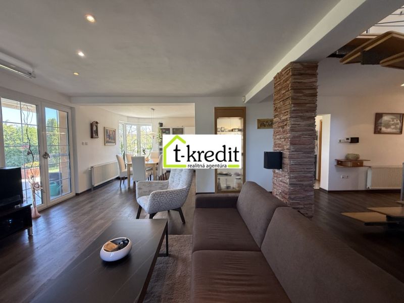 Living room with wood-patterned flooring and a dining area in a family house.