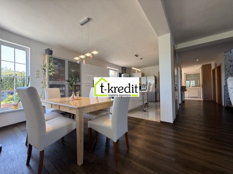 Interior of a family house with a dining room, kitchen, and wooden decor flooring.