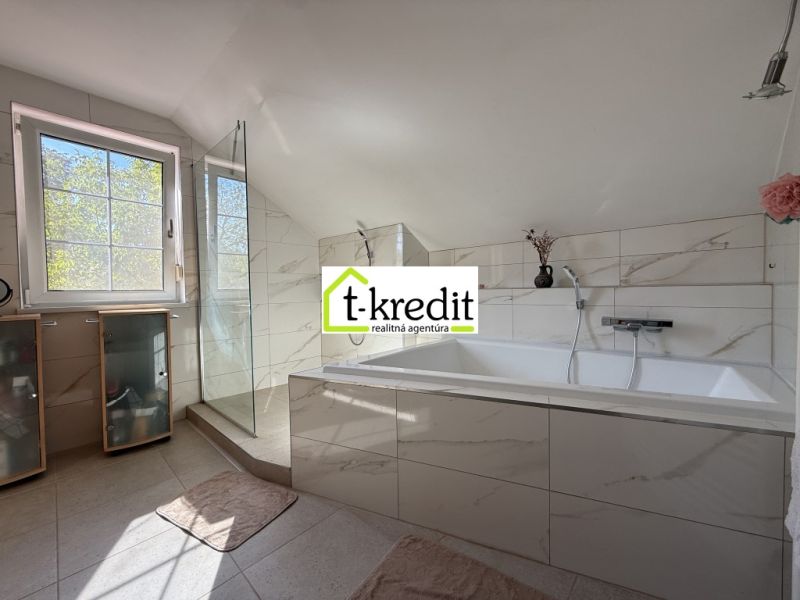 A bathroom in a family house with a bathtub and a shower, surrounded by tiles.