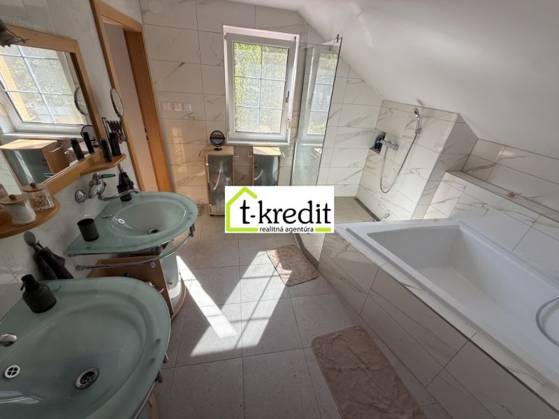 A bathroom in a family house with two sinks, a bathtub, and a shower.