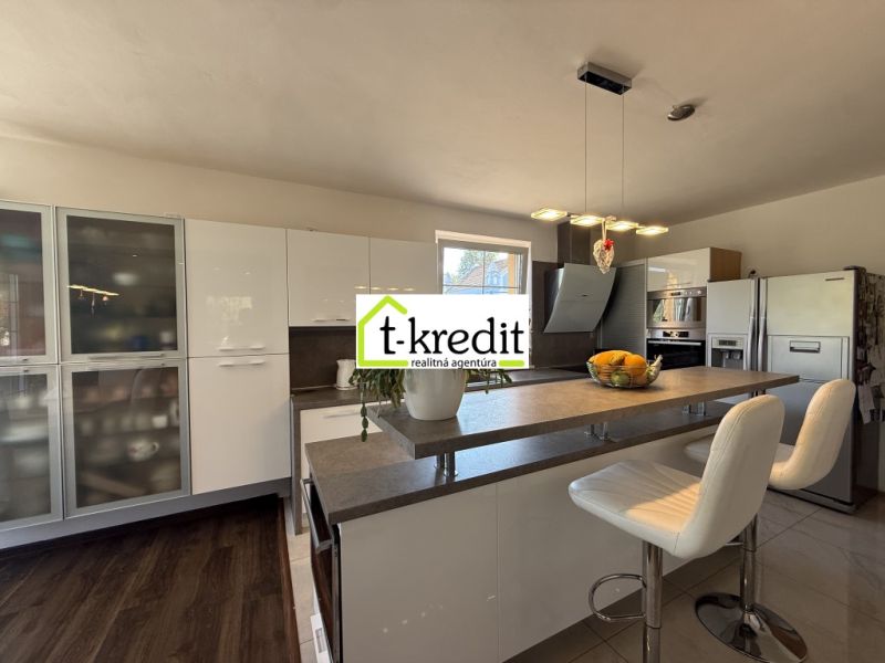 A kitchen in a family house with a bar counter and a wooden decor floor.