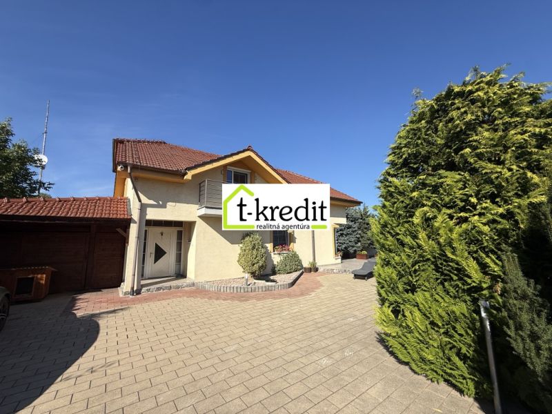 A family house in Zlaté Moravce with a driveway, a balcony, and green trees.