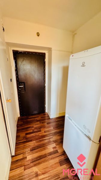 Interior with a refrigerator and a wooden decor floor in a studio apartment.