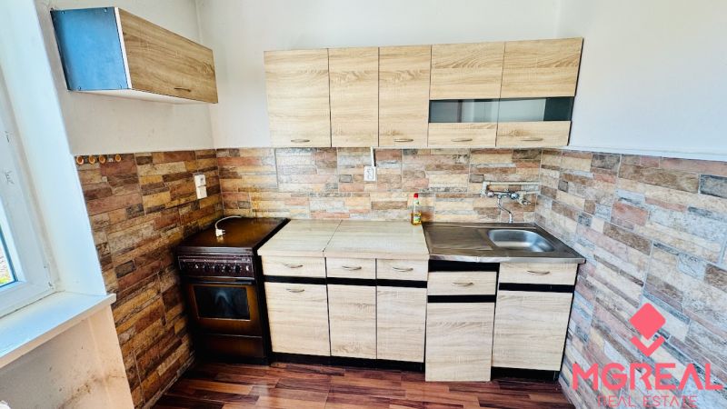 A kitchen in a studio apartment with a wooden decor and stone wall cladding.
