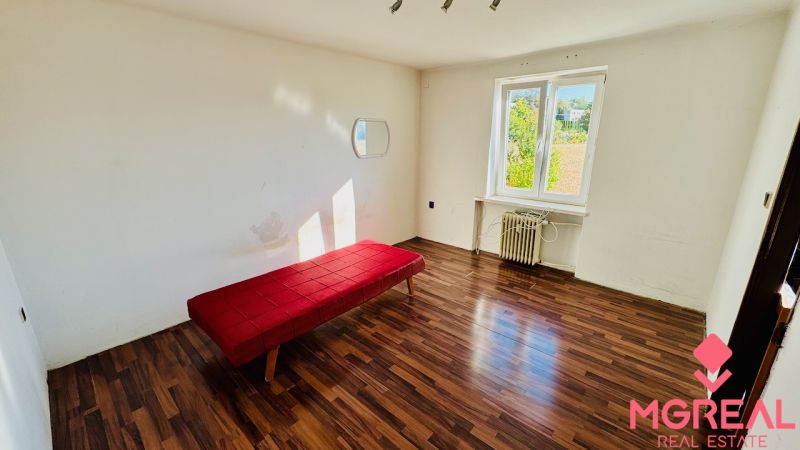 A simple interior of a one-room apartment with a wooden decor floor and a red sofa.