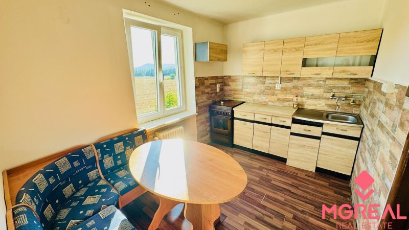 A kitchen in a studio apartment with a kitchen unit, wooden decor flooring, and a view.