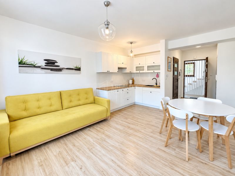 Living room in a studio apartment with wood-patterned flooring and a yellow sofa.