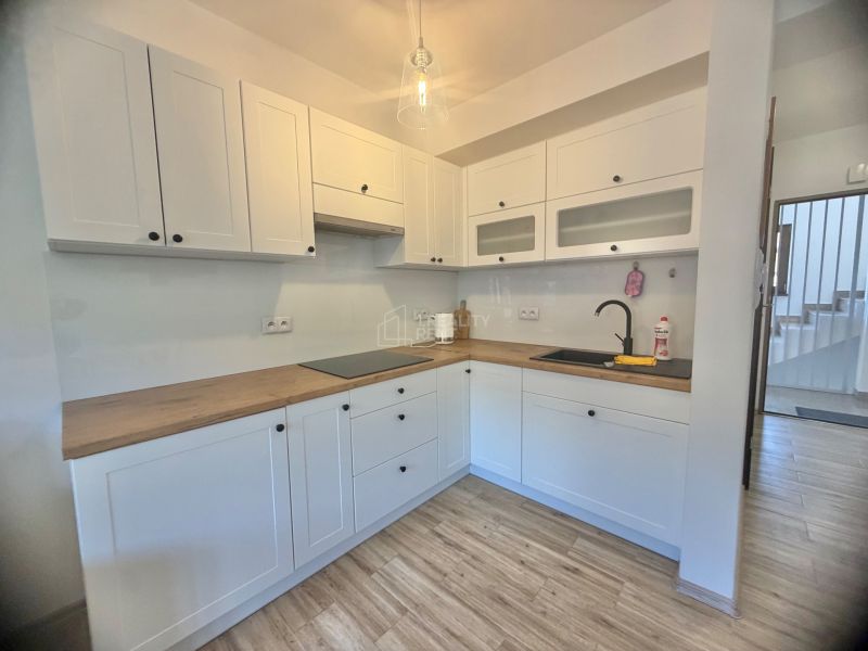 A kitchen in a studio apartment with white cabinets and a wood-patterned floor.