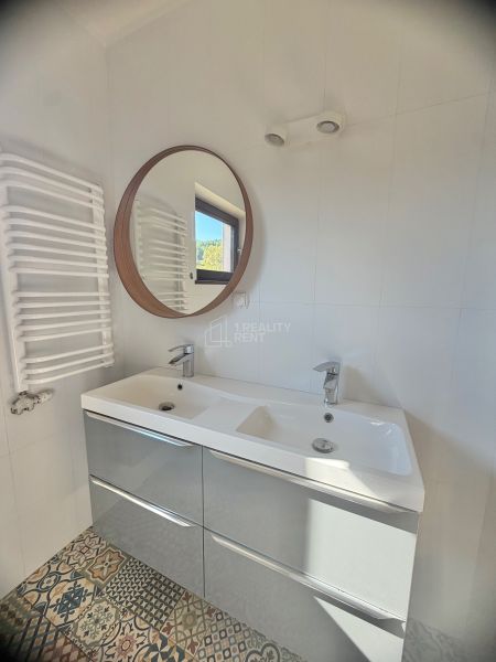 The bathroom in the studio apartment includes a double sink, a round mirror, and patterned tiles.