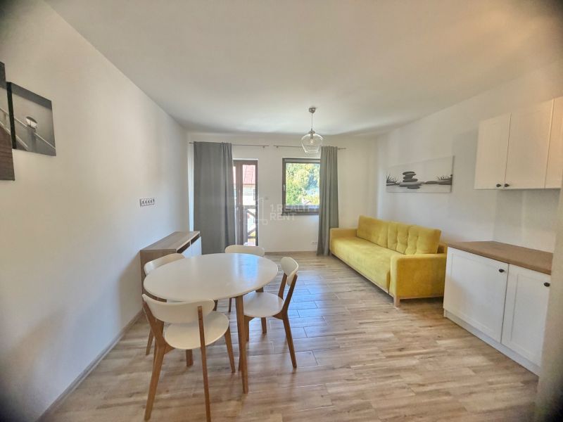 1-bedroom apartment with wood-patterned flooring, yellow sofa, and white furniture.