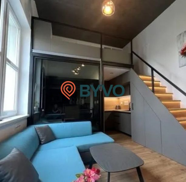 Living room with a blue sofa and staircase in a studio apartment.