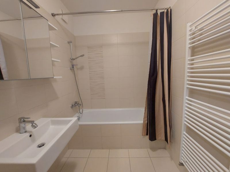 A bathroom in a 3-room apartment with a bathtub, a sink, and a ladder radiator.