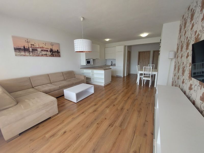 Living room with wood-patterned flooring and a corner sofa in a three-room apartment.