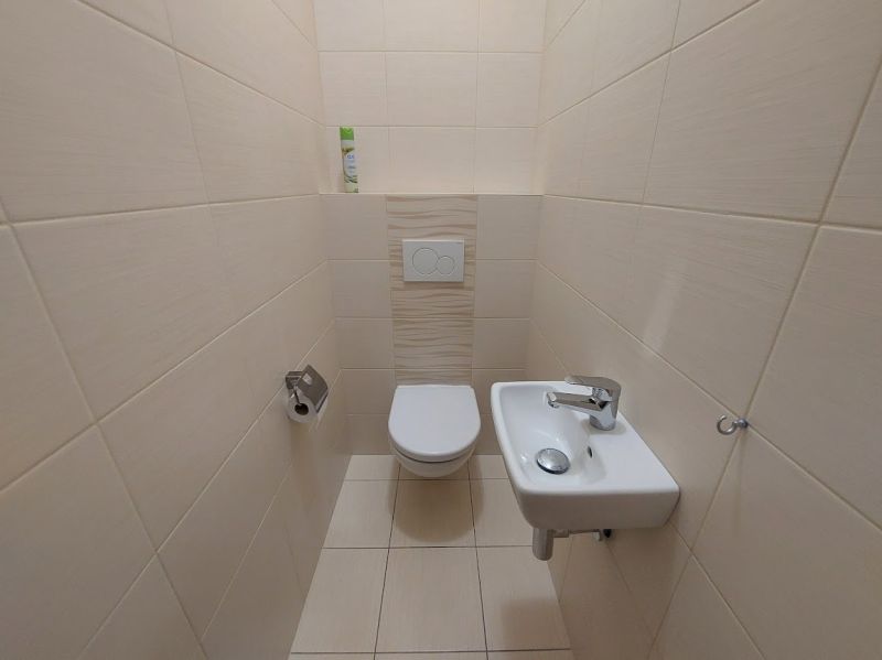 A toilet with a sink in the interior of a 3-room apartment, tiled walls.
