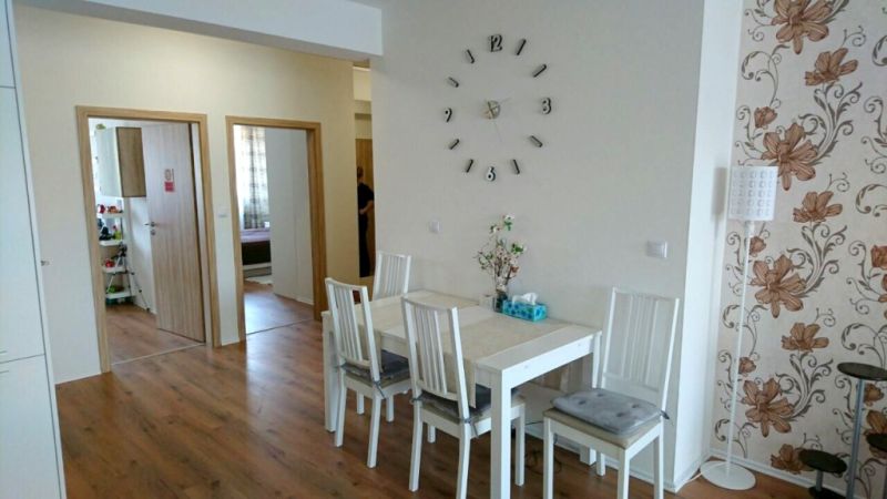 Dining room in a 3-room apartment with a wood-patterned floor and floral wallpaper.