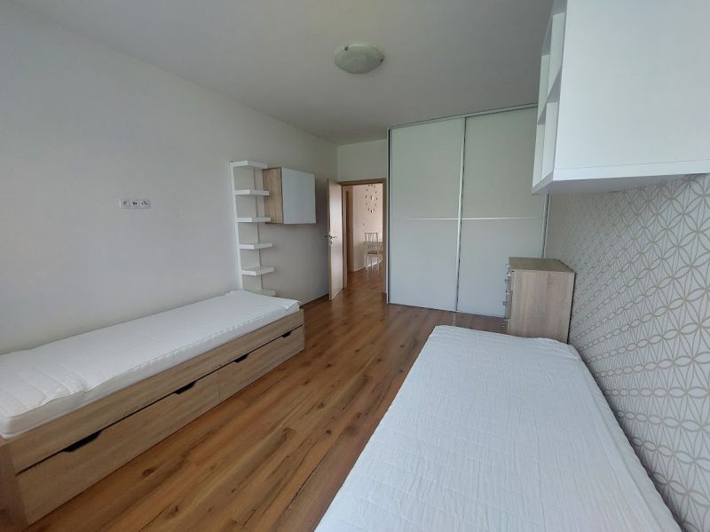 A bedroom in a 3-room apartment with a wooden decor floor, two beds, and a built-in wardrobe.