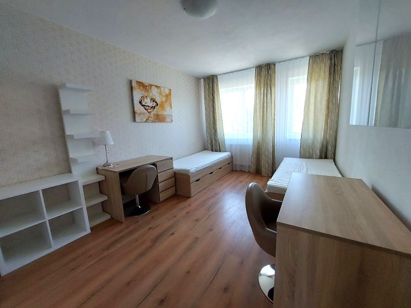 A room with two beds, tables, and a floor with a wooden decor in a 3-room apartment.